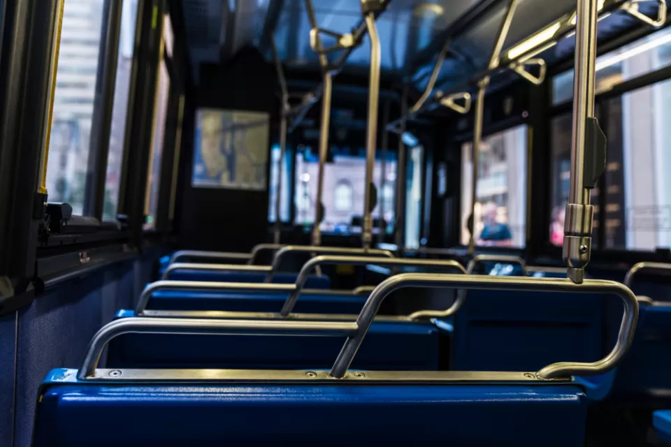 Close-up view of empty bus from behind seat. Seats have blue upholstery